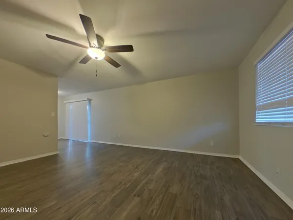 an empty room with wooden floor fan and windows