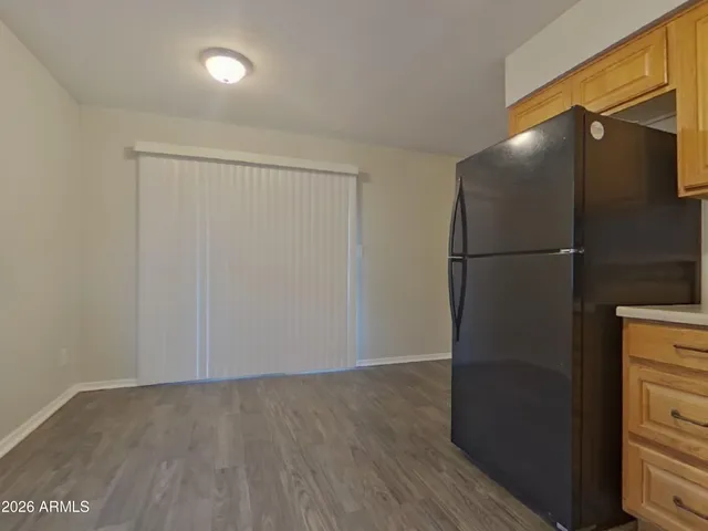a view of a refrigerator in kitchen and an empty room