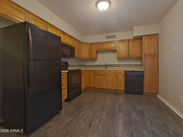 a kitchen with stainless steel appliances granite countertop a refrigerator a sink dishwasher a stove with wooden cabinets