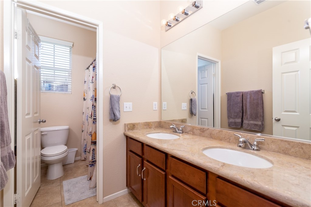 27336 Brandon Lane Temecula, CA 92591 - Photo 21 of 49 a bathroom with a granite countertop double vanity sink a mirror and a toilet