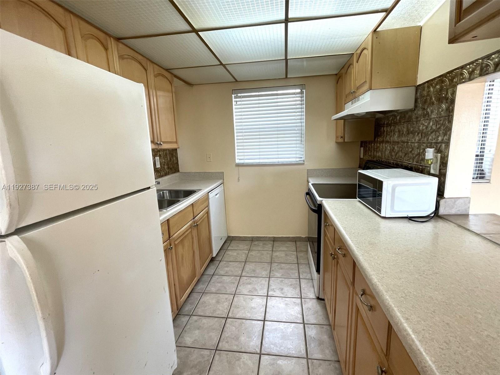 1720 North Congress Avenue, Unit 310 West Palm Beach, FL 33401 - Photo 11 of 18 a kitchen with stainless steel appliances granite countertop a sink a stove a refrigerator a washer dryer and white cabinets