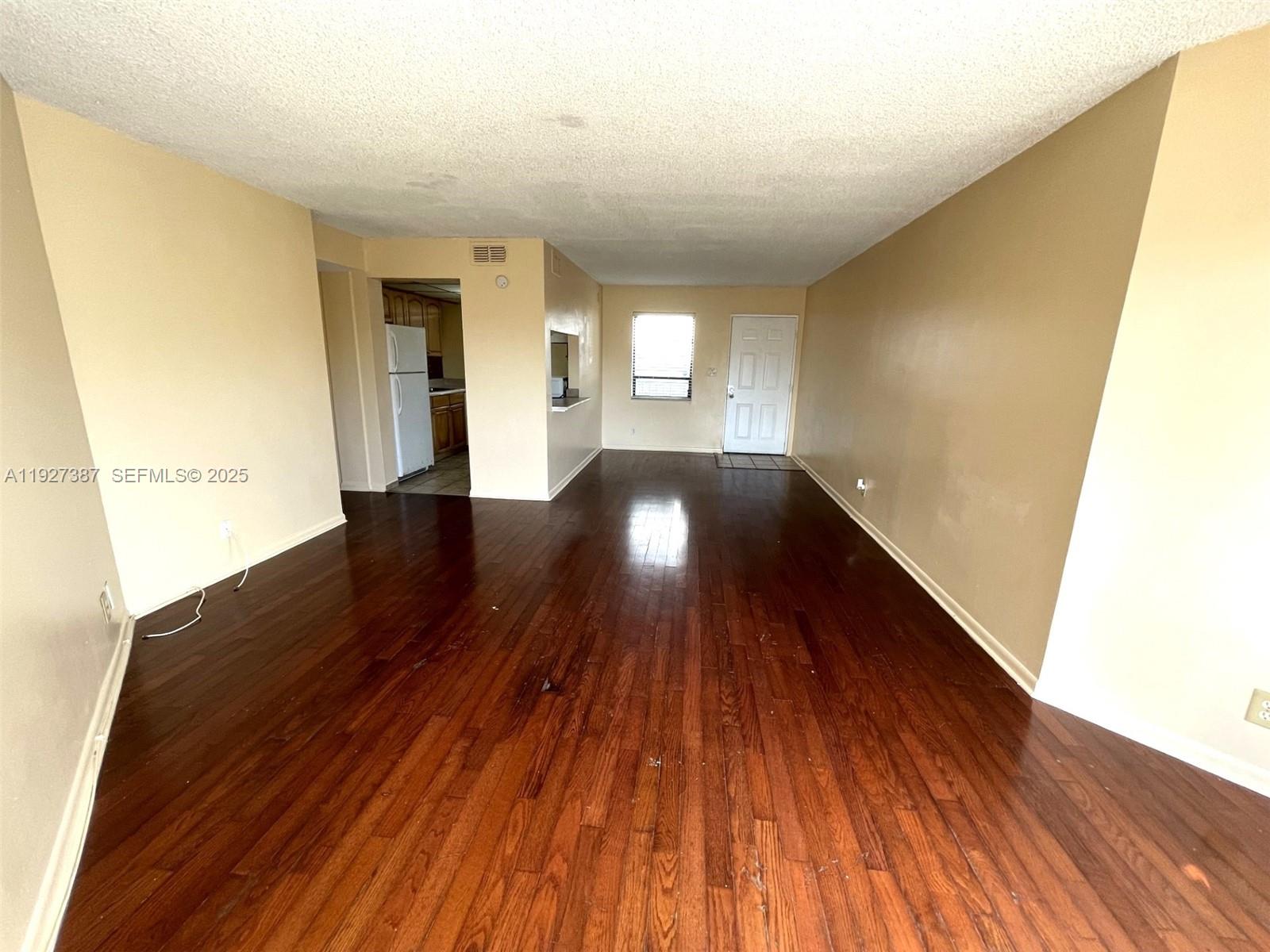 1720 North Congress Avenue, Unit 310 West Palm Beach, FL 33401 - Photo 5 of 18 a view of an empty room with wooden floor and a window