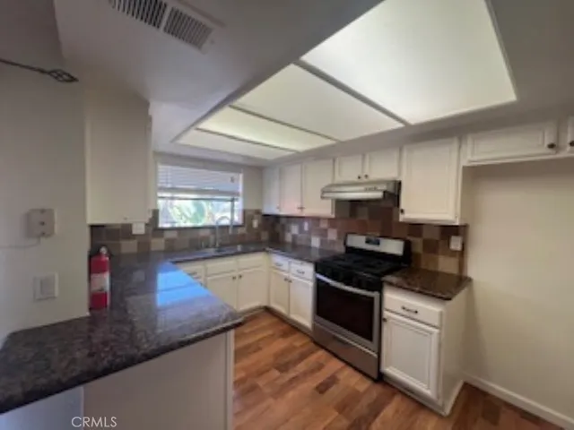 a kitchen with granite countertop stainless steel appliances a sink a stove and cabinets