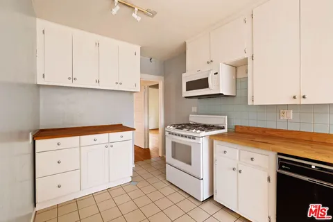 a kitchen with granite countertop white cabinets and white appliances
