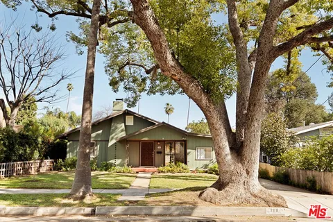 a front view of a house with a tree and yard