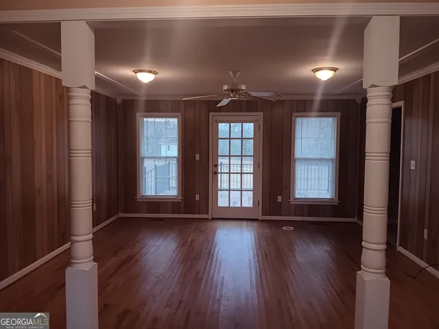 a view of an empty room with wooden floor and a window
