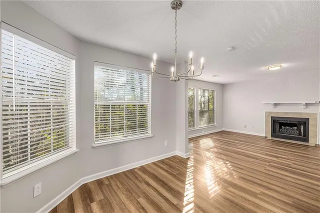 a view of an empty room with wooden floor fireplace and a window