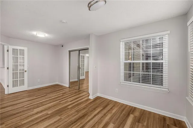 a view of an empty room with wooden floor and a window