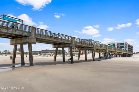 a view of house with sign board and palm trees