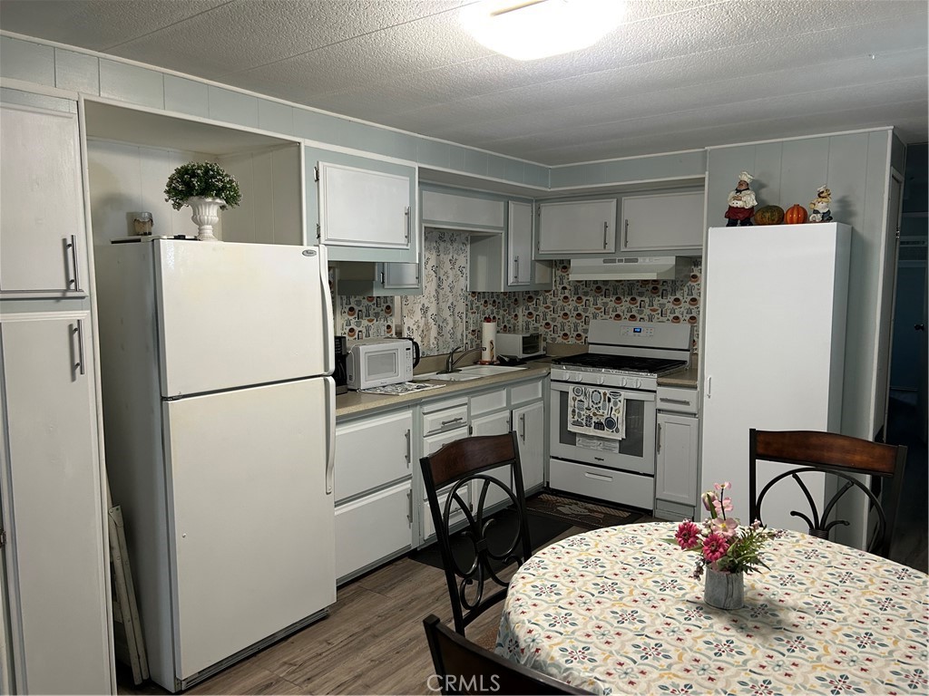 3734 Pacific Street, Unit 40 Highland, CA 92346 - Photo 6 of 35 a kitchen with stainless steel appliances granite countertop a refrigerator a stove a sink dishwasher and a dining table with wooden floor