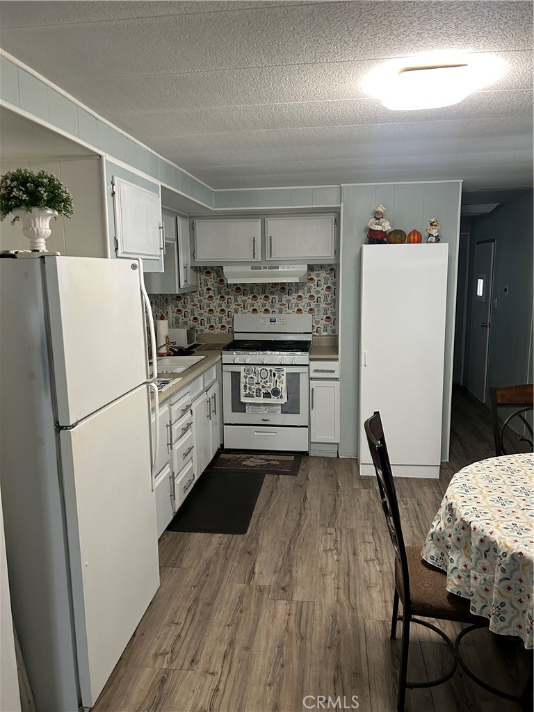 3734 Pacific Street, Unit 40 Highland, CA 92346 - Photo 8 of 35 a kitchen with a refrigerator a stove a sink dishwasher and white cabinets with wooden floor