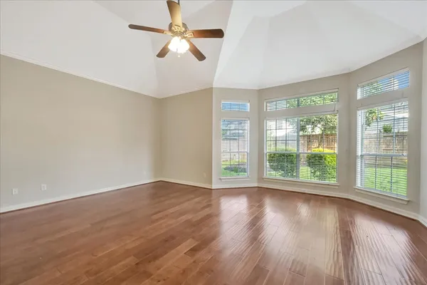 an empty room with wooden floor and windows