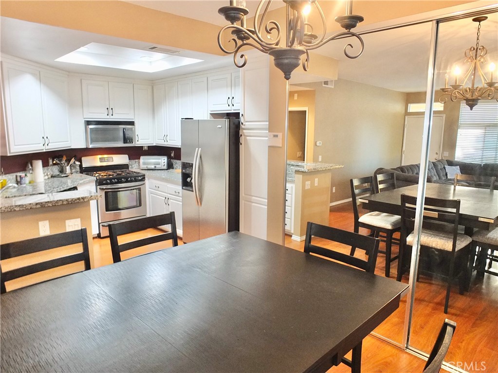 19431 Rue De Valore, Unit 19B Lake Forest, CA 92610 - Photo 11 of 24 a kitchen with stainless steel appliances kitchen island granite countertop a table chairs refrigerator and microwave