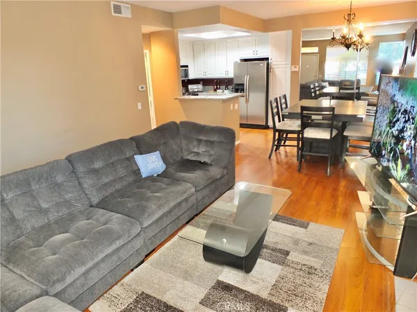 a living room with couches and kitchen view with wooden floor