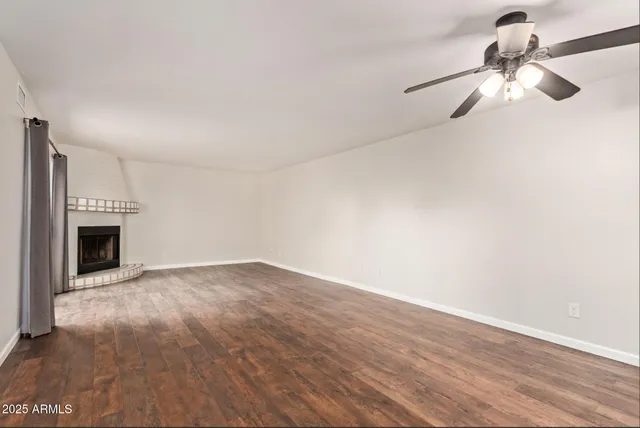 a view of empty room with wooden floor and fireplace