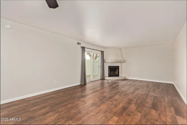 a view of an empty room with wooden floor and fireplace