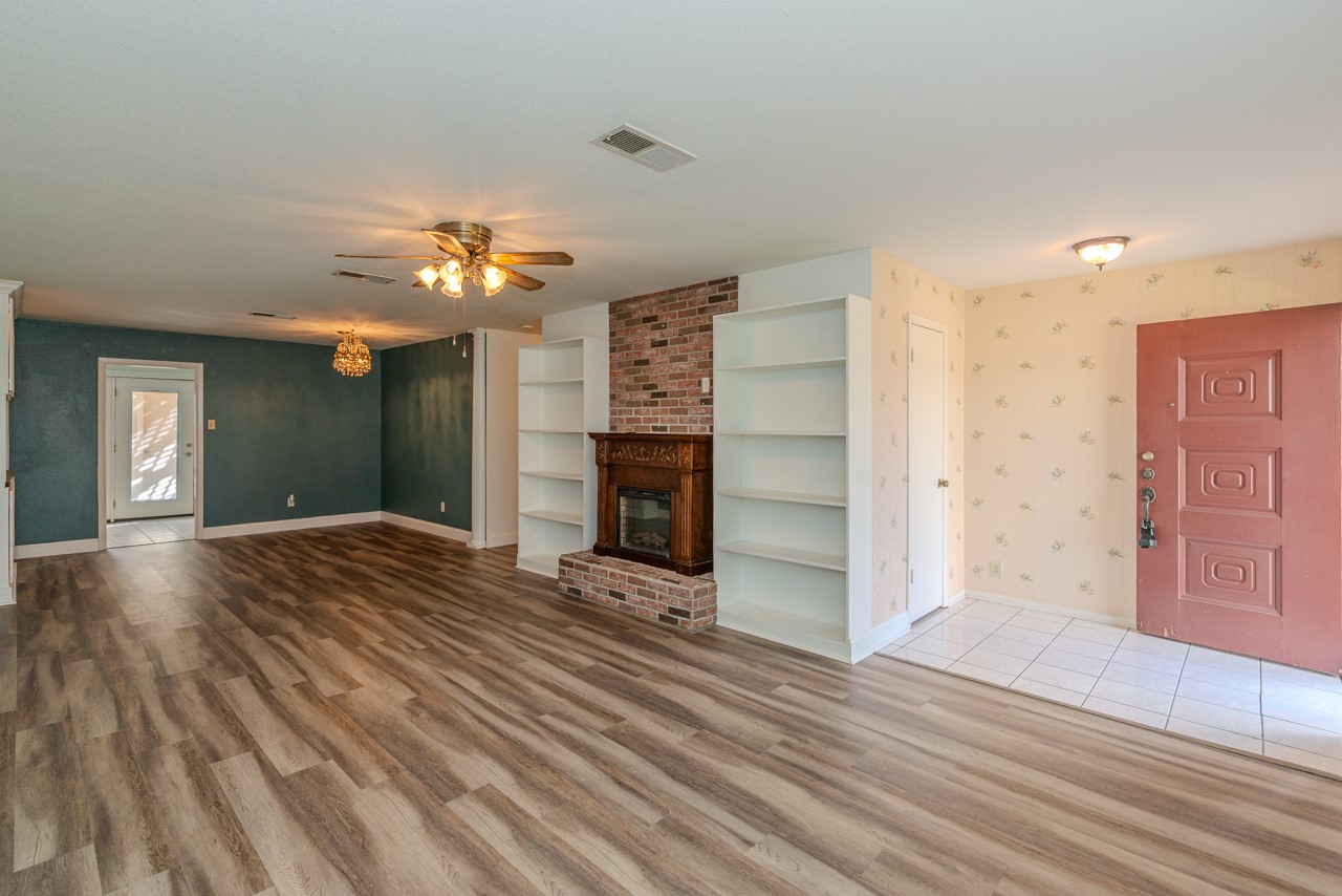 5975 Meadow Way Beaumont, TX 77707 - Photo 3 of 18 a view of a livingroom with a fireplace a chandelier and stairs