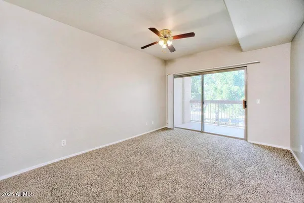 a view of an empty room with chandelier fan and fire place