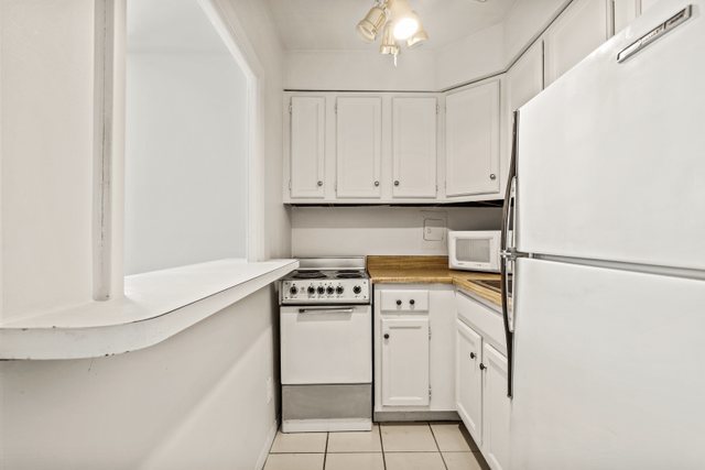 6118 North Sheridan Road, Unit 206 Chicago, IL 60660 - Photo 6 of 18 a kitchen with white cabinets and white appliances