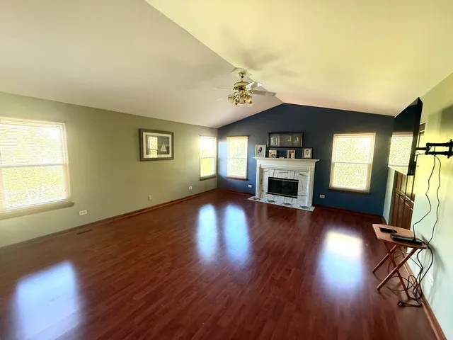 an empty room with wooden floor fireplace and windows
