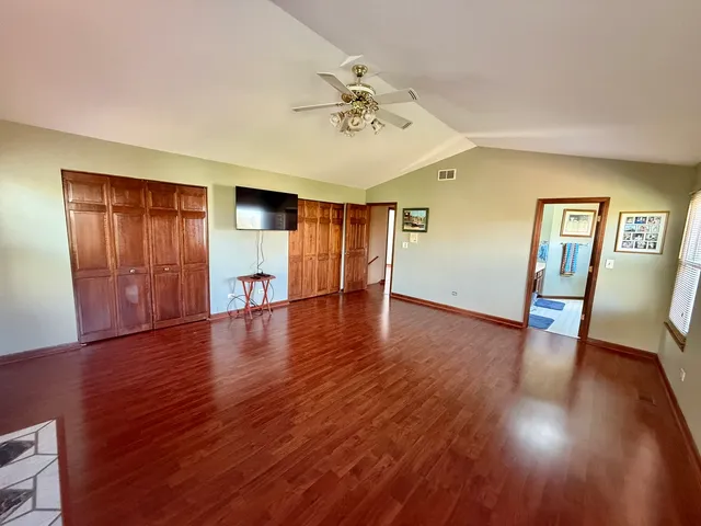 a view of empty room with wooden floor and ceiling fan