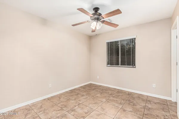 an empty room with chandelier fan and windows