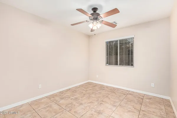 an empty room with chandelier fan and windows