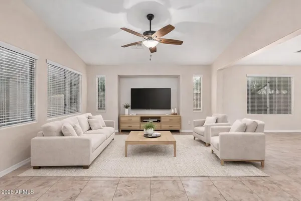 a living room with furniture ceiling fan and a large window
