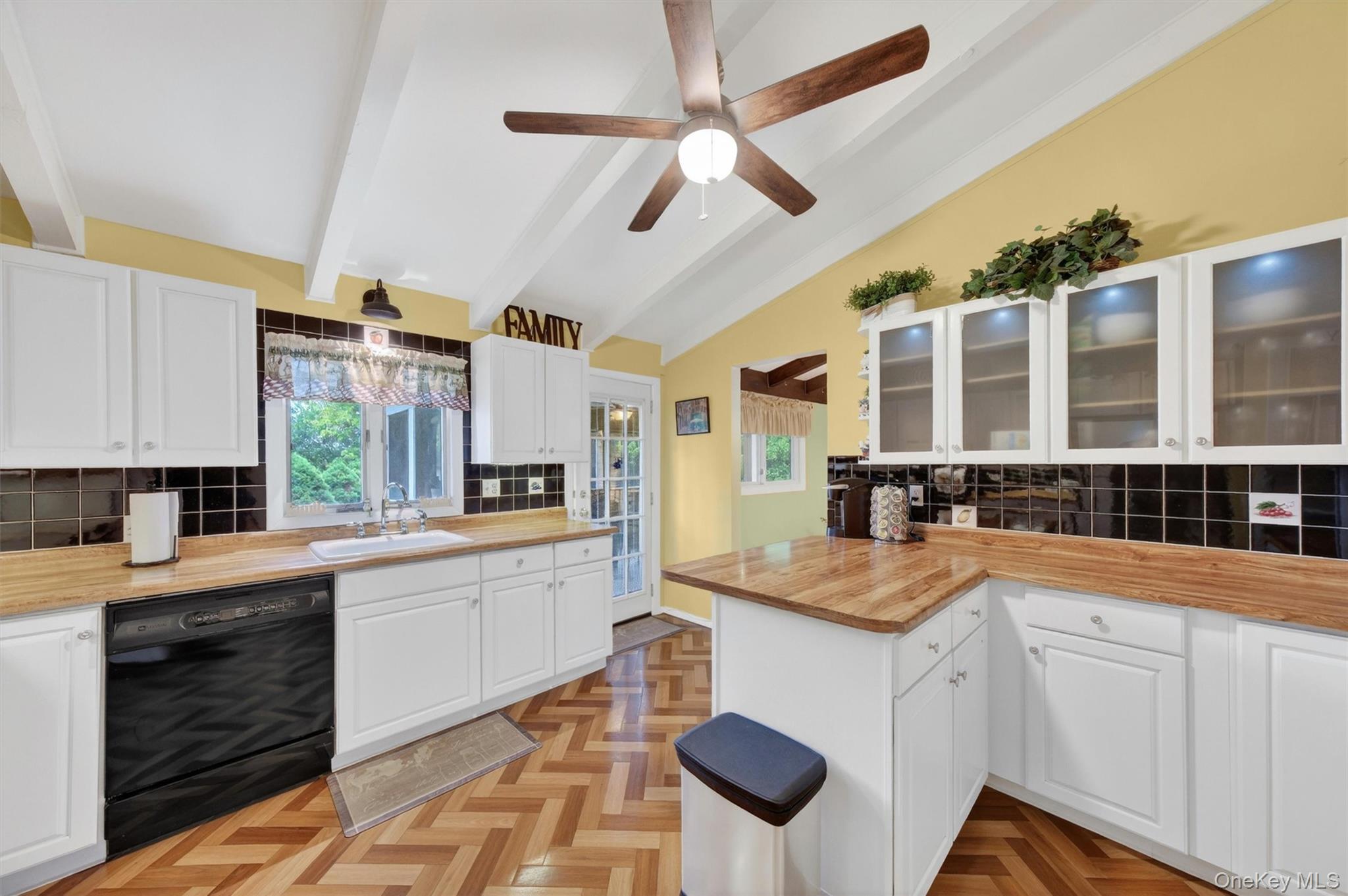 1 Rockledge Road Poughkeepsie, NY 12601 - Photo 10 of 36 Kitchen featuring vaulted ceilings with exposed beams, wood-finish flooring in a herringbone pattern, white cabinetry, breakfast bar, tile backsplash, cabinet lighting and light wood-finish countertops