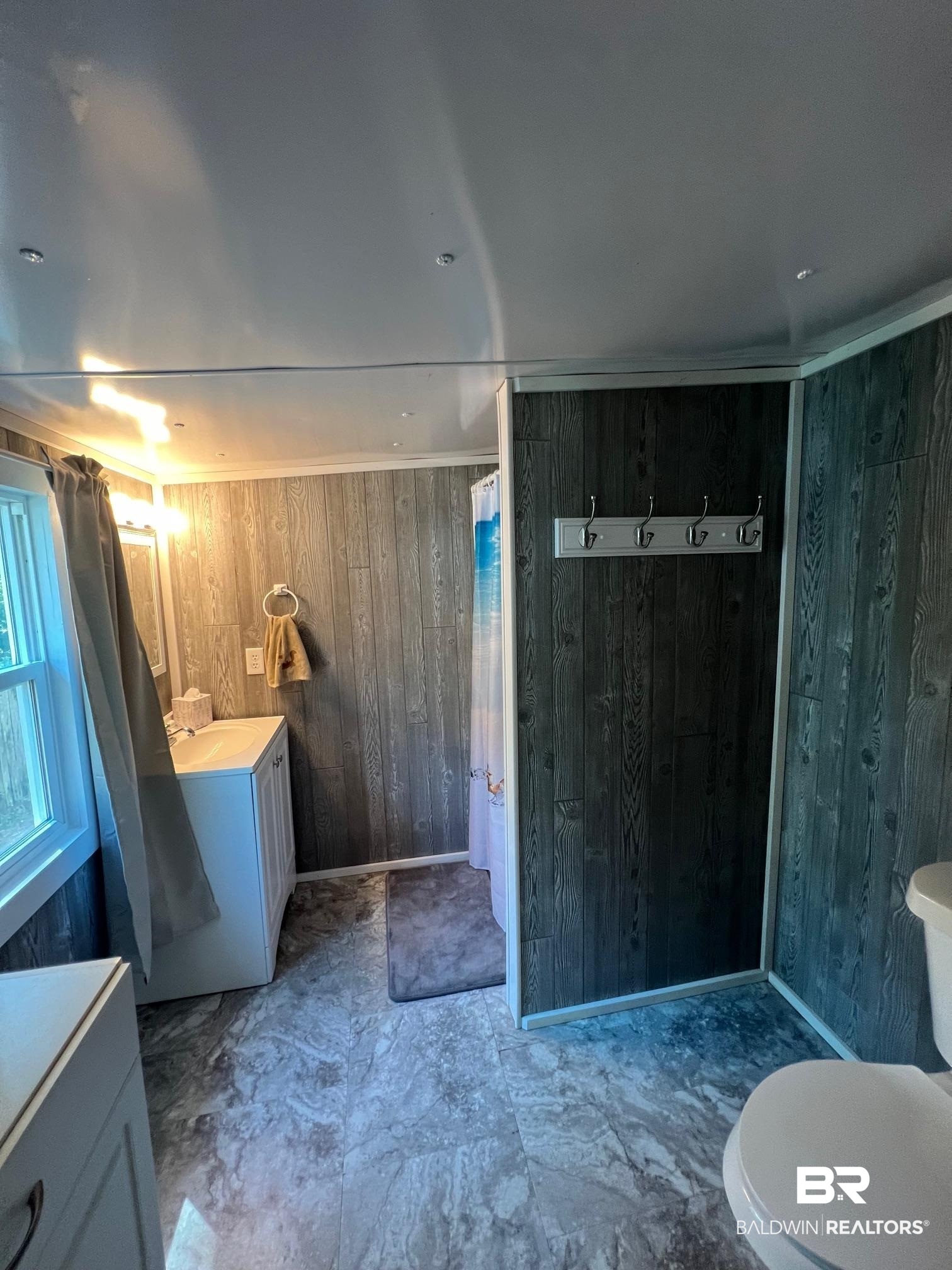 1420 Ridgewood Circle Lillian, AL 36549 - Photo 13 of 41 Bathroom featuring wood walls, toilet, a shower with shower curtain, and vanity