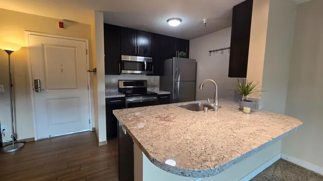 a kitchen with stainless steel appliances granite countertop a sink refrigerator and microwave