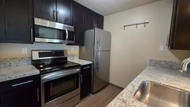 a kitchen with stainless steel appliances granite countertop a stove microwave and refrigerator