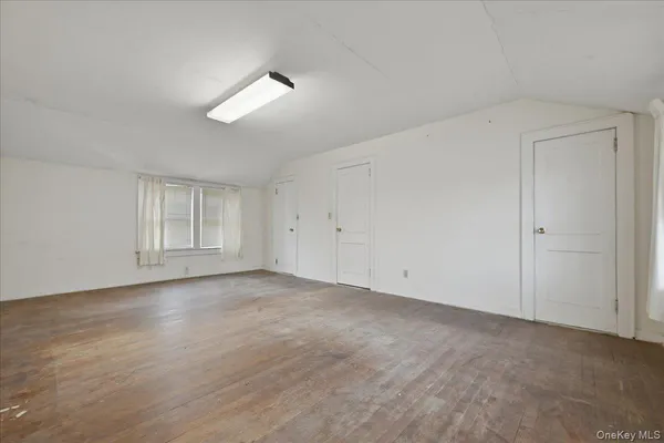 a view of an empty room with wooden floor and window