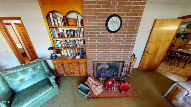 a living room with couches bookshelf and a fireplace with wooden floor