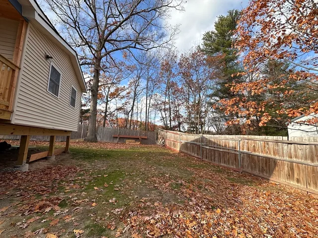 a view of backyard with wooden fence and large trees