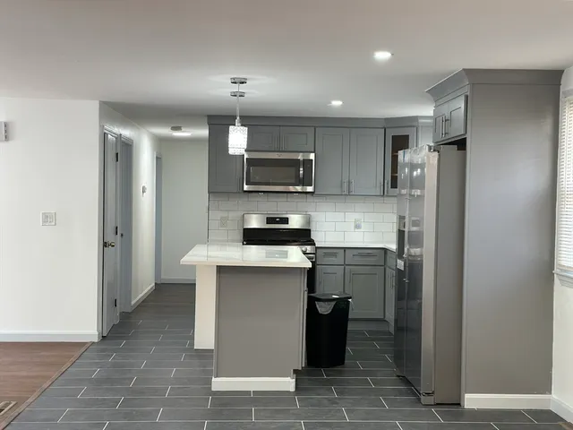 a kitchen with stainless steel appliances granite countertop a refrigerator a sink a stove a microwave and island