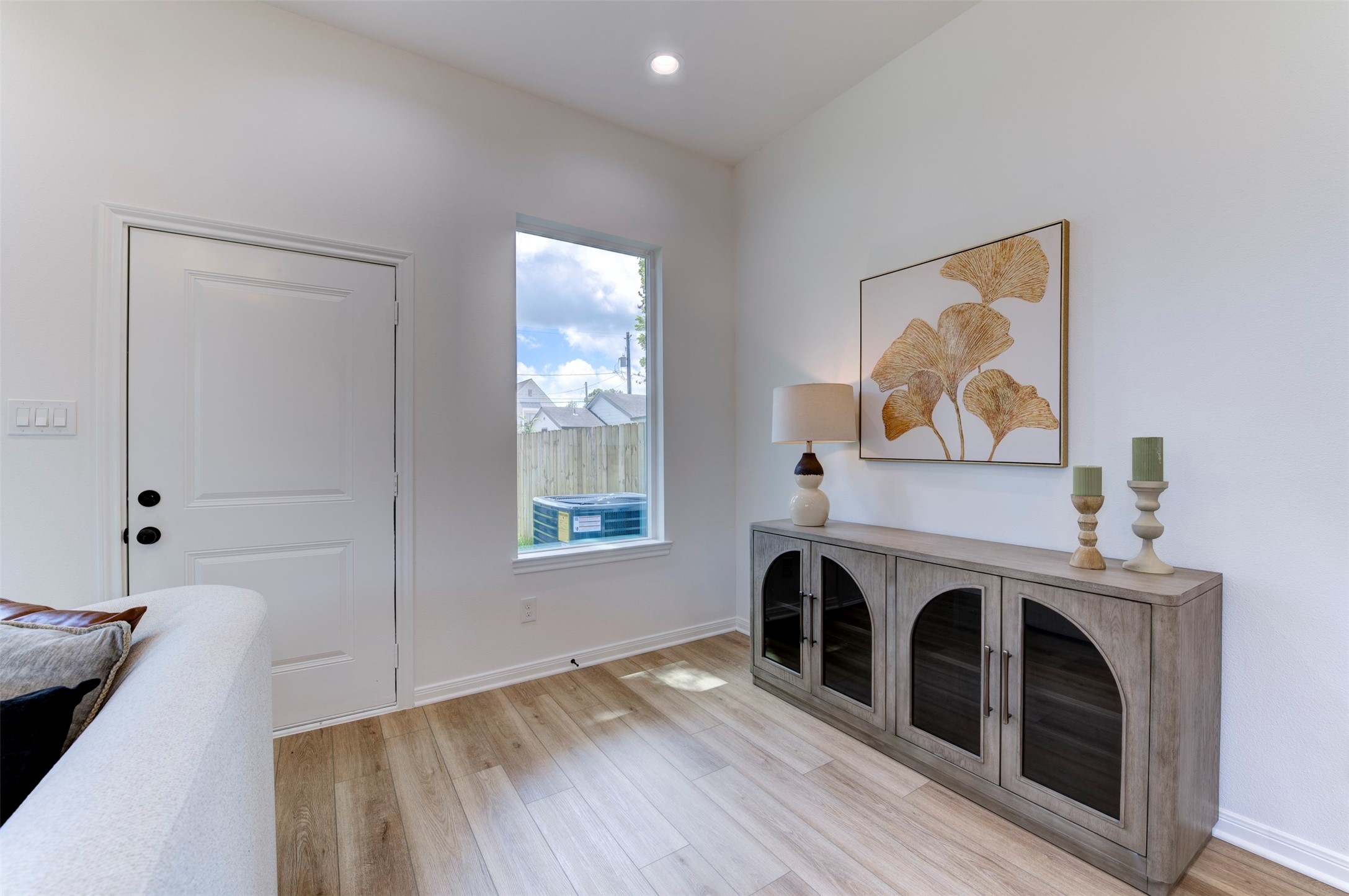 6807 Paris Street Houston, TX 77021 - Photo 14 of 50 Living room sitting nook with floor-to-ceiling windows, hardwood floors, recessed lighting, and open backyard views with wood privacy fence.