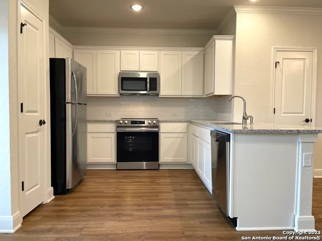 a kitchen with stainless steel appliances white cabinets and wooden floor