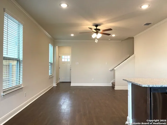 a view of empty room with wooden floor and fan