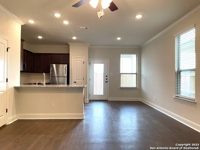 a living room with stainless steel appliances granite countertop wooden floors and couches