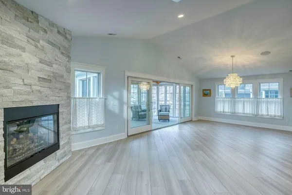 an empty room with wooden floor fireplace and windows