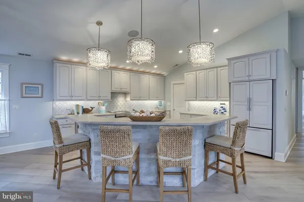 a large kitchen with kitchen island stainless steel appliances a chandelier and wooden floor