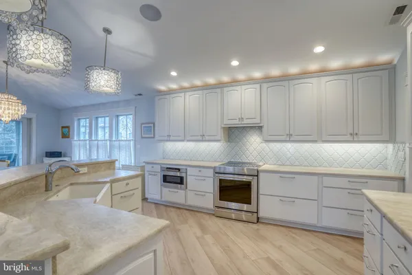 a large kitchen with stainless steel appliances granite countertop a large kitchen island a stove and a wooden floors