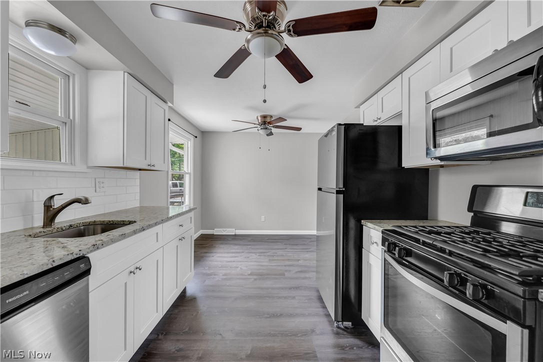 8043 Munson Road Mentor, OH 44060 - Photo 14 of 27 Kitchen featuring white cabinetry, dark wood-type flooring, appliances with stainless steel finishes, sink, and tasteful backsplash