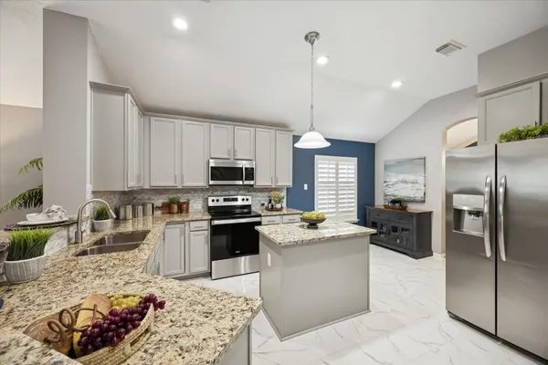 a kitchen with stainless steel appliances granite countertop a sink stove refrigerator and window