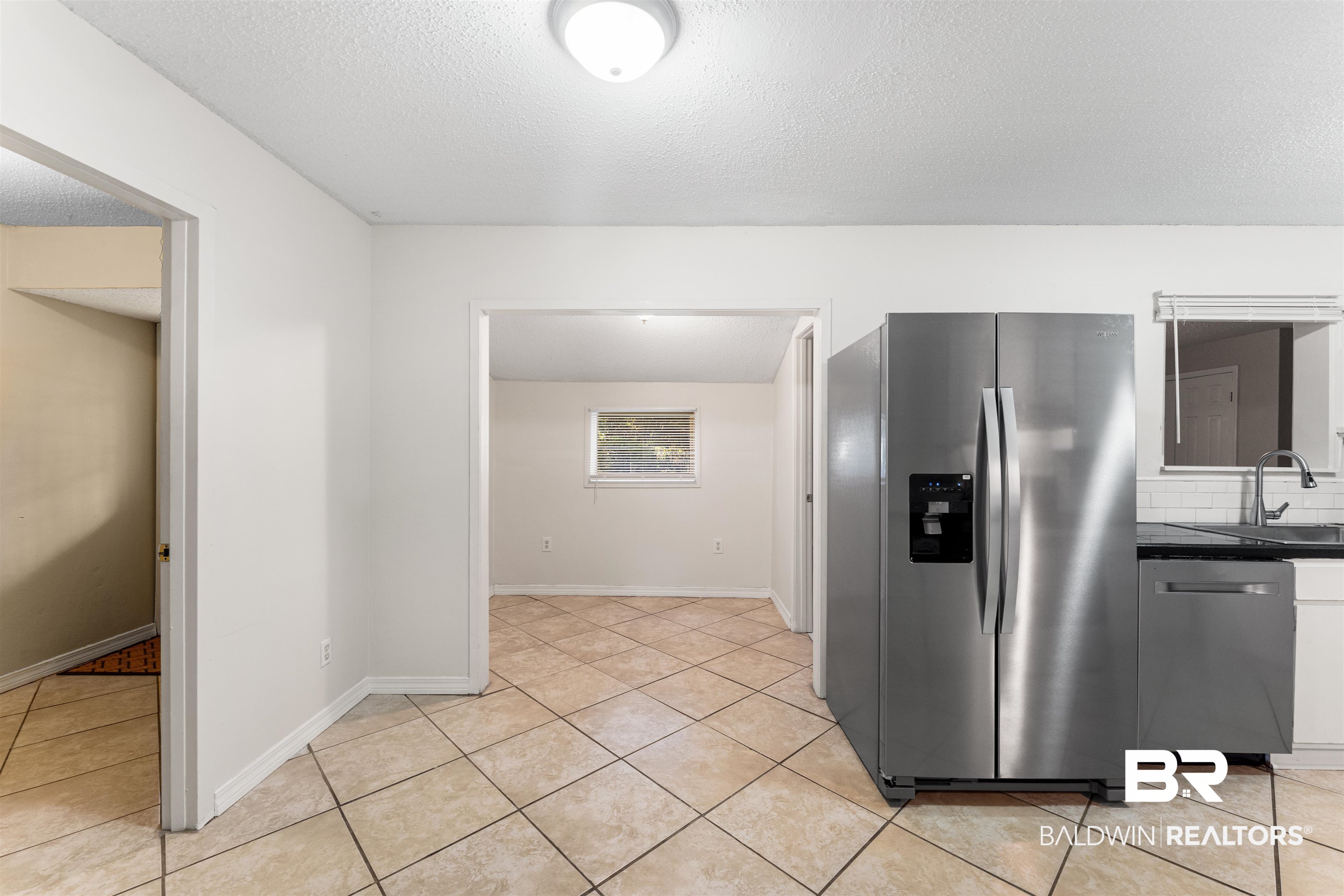 5551 Springer Court Theodore, AL 36582 - Photo 4 of 37 Kitchen featuring appliances with stainless steel finishes, a textured ceiling, light tile patterned flooring, and tasteful backsplash