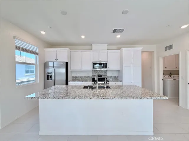 a kitchen with stainless steel appliances granite countertop a sink a refrigerator and a granite counter tops