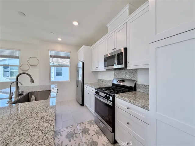 a kitchen with stainless steel appliances granite countertop a stove a sink and a microwave