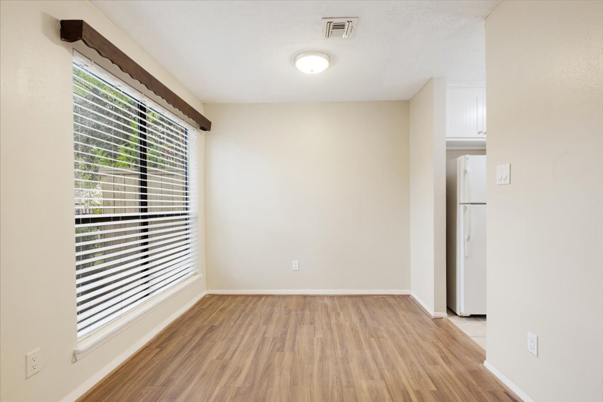 3502 Ocee Street, Unit 3502 Houston, TX 77063 - Photo 4 of 28 Bright room with large window, wood flooring, and neutral walls. Adjacent to a kitchen area with visible refrigerator. Perfect for a dining space or small living area.