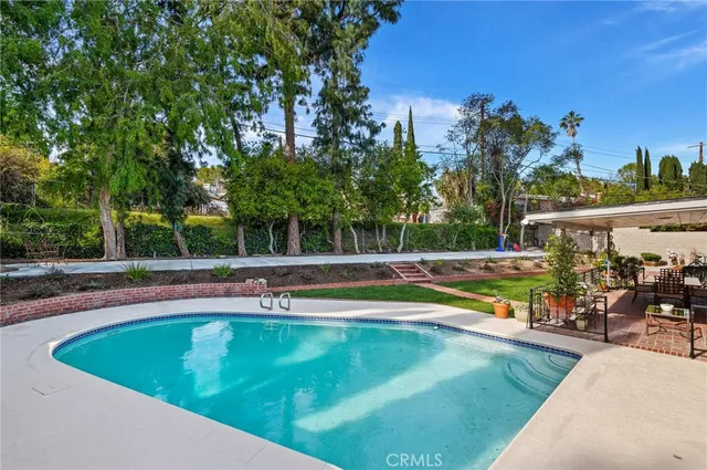 a view of a swimming pool with an outdoor seating and a forest
